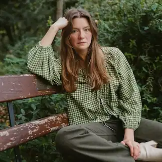 Portrait of a woman with long dark hair among blooming tree branches, used as an analyzing example in an AI people search tool to match and identify individuals from reference images.